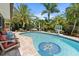 Beautiful Kidney-shaped pool surrounded by lush landscaping and brick pavers with inground basketball net at 10515 Hetrick W Cir, Largo, FL 33774
