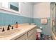 Bathroom featuring a large sink and counter, blue tiled walls and a shower with glass door and a mounted towel rack at 11308 N Hamner Ave, Tampa, FL 33612
