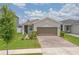 Charming single-story home featuring a well-manicured lawn, lush landscaping, and a brick-paved driveway at 11830 Brighton Knoll Loop, Riverview, FL 33579