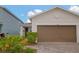 Close-up of the front exterior showcasing the home's neutral paint, brick-paved driveway and two car garage at 11830 Brighton Knoll Loop, Riverview, FL 33579