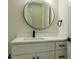 Stylish bathroom featuring a modern vanity with marble countertop, round mirror, and sleek black hardware at 12484 Cross St, Largo, FL 33773