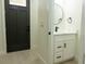 Half bathroom featuring a black faucet, white vanity, round mirror, and modern fixtures at 12484 Cross St, Largo, FL 33773