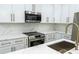 Modern kitchen features white cabinetry, stainless steel appliances, gold hardware, and marble countertops at 12484 Cross St, Largo, FL 33773