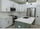Modern kitchen with white cabinets, stainless steel appliances, gray-green island and marble backsplash at 12484 Cross St, Largo, FL 33773