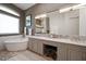 Bright bathroom featuring a soaking tub, granite counters, gray cabinets, and a large mirror at 14 Sunset Bay Dr, Belleair, FL 33756