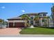 Elegant home featuring a spacious driveway, lush lawn, and meticulously landscaped front yard with palm trees at 14 Sunset Bay Dr, Belleair, FL 33756