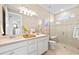 Bright bathroom features a glass enclosed shower, double vanity, and light beige tile flooring at 14313 Eagle Branch Dr, Nokomis, FL 34275