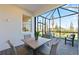 Screened lanai with a table and chairs overlooking a grassy backyard area with palm trees at 14313 Eagle Branch Dr, Nokomis, FL 34275