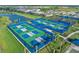 Aerial view of community pickleball courts with blue surrounds and water views in Talon Preserve at 14313 Eagle Branch Dr, Nokomis, FL 34275