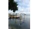 Exterior shot of a dock with a boat lift and boats docked, capturing waterfront lifestyle and boating access at 14555 N Bayshore Dr, Madeira Beach, FL 33708