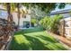 The backyard features artificial grass, lush landscaping, and a view of the home at 16107 Dawnview Dr, Tampa, FL 33624