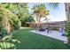 Backyard featuring artificial grass, a fire pit, and a view of a palm tree at 16107 Dawnview Dr, Tampa, FL 33624