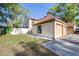 Exterior showcasing a two-car garage, a green lawn, and white fence surrounded by trees at 16107 Dawnview Dr, Tampa, FL 33624