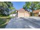 Attached two-car garage featuring a spacious driveway with some grass on the side of the house at 16107 Dawnview Dr, Tampa, FL 33624