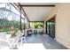 The screened-in patio is comfortably arranged with chairs, a table, and a leafy green view at 16107 Dawnview Dr, Tampa, FL 33624