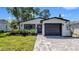 Charming home with a well-manicured lawn, paver driveway, and dark trim accents at 1710 Shore Acres Ne Blvd, St Petersburg, FL 33703