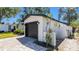 Exterior view of the garage, showing the black door, brick paved driveway, and new landscaping at 1710 Shore Acres Ne Blvd, St Petersburg, FL 33703