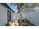 Well-manicured side yard with manicured landscape, stone pathway, and a white privacy fence at 1710 Shore Acres Ne Blvd, St Petersburg, FL 33703