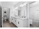 Bright bathroom featuring double sinks, white cabinetry, modern fixtures, and a separate toilet room at 17249 Star Banks St, Wimauma, FL 33598