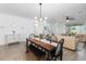 Open-concept dining room with modern chandelier, bench seating and access to living room at 17249 Star Banks St, Wimauma, FL 33598