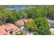 Aerial view showcasing a home with tile roof surrounded by mature trees near a lake at 1940 Floresta View Dr, Tampa, FL 33618