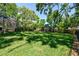 Spacious backyard featuring a trampoline and screened-in pool, surrounded by mature trees and lush landscaping at 1940 Floresta View Dr, Tampa, FL 33618
