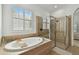 Bright bathroom featuring a soaking tub, separate glass enclosed shower, large window and neutral tile work at 1940 Floresta View Dr, Tampa, FL 33618