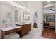 Bright bathroom with a vanity, stool, and large mirror, with a glimpse into the bedroom at 19830 Strathmore Pl, Land O Lakes, FL 34638