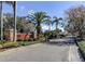 Elegant community entrance with stone signage, lush landscaping, and palm trees under a clear blue sky at 19830 Strathmore Pl, Land O Lakes, FL 34638