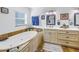 Spa-like bathroom featuring an elegant soaking tub, double sink vanity, framed mirror, and a window for natural light at 1990 59Th N St, St Petersburg, FL 33710