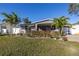 Charming single-story home with a well-manicured lawn and lush landscaping, including palm trees at 1990 59Th N St, St Petersburg, FL 33710