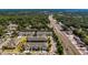 An aerial view shows several blocks of new townhomes near mature trees and a main road with bustling traffic at 2013 Sunset Wind Loop, Oldsmar, FL 34677