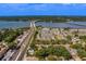 An aerial view displays modern townhouses close to a bridge, waterfront, and tree cover for serene community living at 2013 Sunset Wind Loop, Oldsmar, FL 34677
