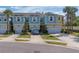 Charming two-story townhome featuring a blue and yellow exterior, attached garages, and well-manicured landscaping at 2013 Sunset Wind Loop, Oldsmar, FL 34677