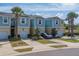 Inviting two-story townhome featuring a blue and yellow exterior, attached garages, and mature palm trees at 2013 Sunset Wind Loop, Oldsmar, FL 34677