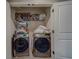 Laundry room featuring a washer and dryer behind white double doors, with shelves full of linens and supplies at 2013 Sunset Wind Loop, Oldsmar, FL 34677