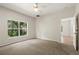 Bright bedroom features neutral carpet, ceiling fan, and large window showcasing a wooded view at 20221 Vintage Oaks Pl, Tampa, FL 33647