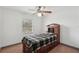 Bedroom with a plaid-covered bed, ceiling fan, wooden floors and a window at 20413 Keene Rd, Wimauma, FL 33598