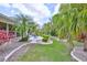 Lush backyard oasis featuring palm trees, meticulously manicured landscaping and a paved patio with outdoor seating at 2216 W Del Webb Blvd, Sun City Center, FL 33573