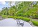 Expansive backyard surrounded by lush trees and bushes, featuring a patio area with seating for outdoor relaxation at 2216 W Del Webb Blvd, Sun City Center, FL 33573