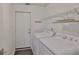 Functional laundry room with washer, dryer, wire shelving, and access door at 2216 W Del Webb Blvd, Sun City Center, FL 33573