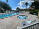 Community pool and hot tub with tiki huts, lounge chairs, and lush tropical landscaping at 2615 Cove Cay Dr # 408, Clearwater, FL 33760