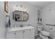Bright bathroom features white cabinets, grey countertop, modern lighting, toilet with accessibility bar, and framed mirror at 297 Lakeview Dr, Tarpon Springs, FL 34689