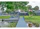 Picturesque view of a dock featuring an entertainment area with lake views, lush trees, and manicured lawn at 297 Lakeview Dr, Tarpon Springs, FL 34689