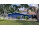 Charming blue home featuring colorful landscaping, a well-manicured lawn, and a welcoming entrance at 297 Lakeview Dr, Tarpon Springs, FL 34689