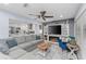 Open living room with gray hardwood floors, gray sectional, fireplace, and view into the modern white kitchen at 297 Lakeview Dr, Tarpon Springs, FL 34689