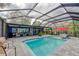 Charming screened-in pool with cozy outdoor seating, a vibrant red umbrella, and a picturesque view of the lake at 297 Lakeview Dr, Tarpon Springs, FL 34689