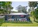 Exterior view of a screened in pool area with a red umbrella at 297 Lakeview Dr, Tarpon Springs, FL 34689