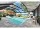 Enclosed pool area features a sparkling pool, brick pavers, comfortable seating, a vibrant red umbrella, and a serene lakeside view at 297 Lakeview Dr, Tarpon Springs, FL 34689