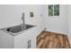 Utility sink with white shaker cabinets in the laundry room with plank tile floors at 3079 Osprey Ln, Clearwater, FL 33762